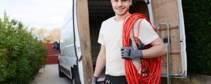 handsome young construction worker with his commercial van on background