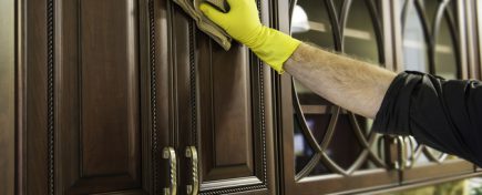 A man cleaning a wooden kitchen cabinet.