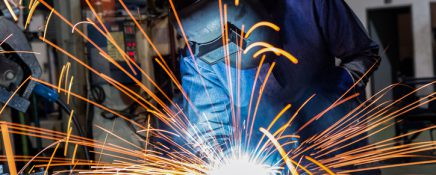 welder is welding assembly car parts in factory with protection mask