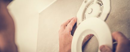 Caucasian Men Installing Electric Air Vent in the Apartment Bathroom. Closeup Photo. Air Ventilation and Climate Control Theme.