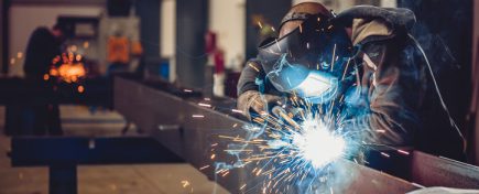 Industrial Welder With Torch and Protective Helmet in big hall welding metal profiles