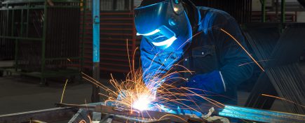 Close-up of a Industrial Welder holding welding Torch with welding sparks.