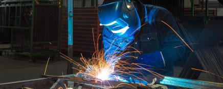 Close-up of a Industrial Welder holding welding Torch with welding sparks.