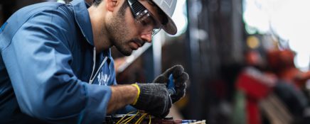 Engineer manual workers standing in a aluminum mill and working together. used professional equipment. Manual workers cooperating while measuring a electronic.