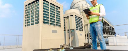 Engineer holding tablet  is checking the cooling tower on the roof of the building to be in good condition.