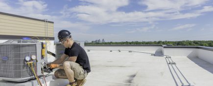 Hvac Tech checking Condenser with Blue Sky Background