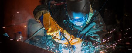 worker welding metal with sparks at factory