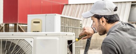 a professional an electrician repairman is repairing a heavy duty central air conditioner unite at the roof top  and wearing blue uniform