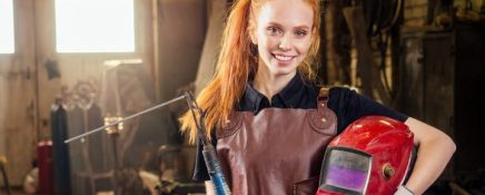 Student in welder training smiling and holding helmet