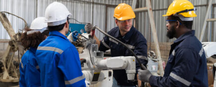 Apprentice millwrights with an experienced construction millwright on a job site after welder college