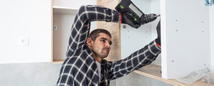 A cabinet maker assembling a kitchen cabinet after cabinet making training