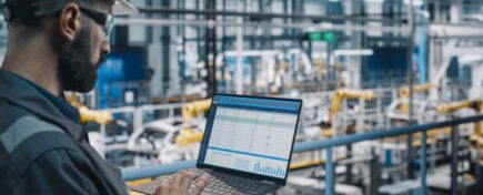 Supply chain manager using a laptop at a car factory