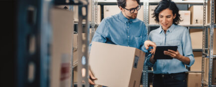 Female inventory manager shows digital tablet information to a worker