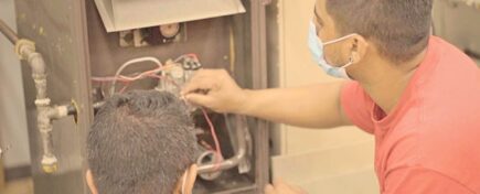 A pair of male HVAC technicians working on a residential HVAC system after completing HVAC technician training