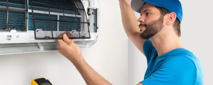 An HVAC training technician graduate replacing an air conditioner part.